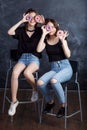 Pretty happy teenage girls with donuts  siting on chairs and having fun. Portrait of joyful smiling girls with donuts on black Royalty Free Stock Photo