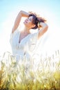 Pretty happy woman in bright clothing among spikes in field Royalty Free Stock Photo
