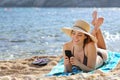 Pretty happy woman reading a smart phone on the beach