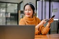 Pretty Asian woman listening to music through her headphones, using smartphone and laptop Royalty Free Stock Photo