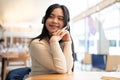 A pretty Asian woman enjoys the music on her headphones while sitting at a table in a coffee shop Royalty Free Stock Photo