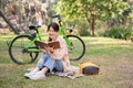 A pretty and happy young Asian woman is relaxing and reading a book in a green park on a bright day Royalty Free Stock Photo