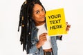 Pretty happy young black woman with dreadlocks with smile in jeans clothes holds a yellow blank banner on a white background. Royalty Free Stock Photo