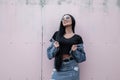 Pretty happy young hipster woman with smile in a stylish denim jacket in a trendy black top in a vintage jeans skirt in sunglasses Royalty Free Stock Photo