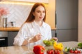 Pretty happy young redhead woman eating fresh vegetarian salad enjoying fresh tasty vegetables sitting at table in Royalty Free Stock Photo