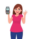 Pretty happy young woman showing/holding pos payment terminal or credit/debit cards swiping machine, gesturing okay/OK sign. Royalty Free Stock Photo