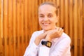 Pretty happy young woman with smartwatch sitting outdoor with wooden panels on background looking at camera with positive facial Royalty Free Stock Photo