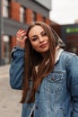 Pretty happy young woman in vintage blue denim jacket walks outdoors. Stylish fashion model beautiful girl posing in the city. Royalty Free Stock Photo