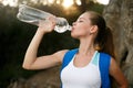 Pretty hiker girl drinking water. Shapely woman tourist with backpack drinking water in nature. Caucasian female drinks