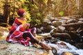 A pretty hipster girl with a plaid plaid on her shoulders in a hat and a yellow sweater and glasses with a mug of coffee