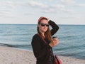 Pretty hipster woman in bandana long hair walking on sea background with coffee cup lifestyle real life travel photo