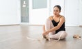 pretty hispanic ballerina smiling while preparing putting on dance ballet toe shoes and getting ready for class or rehearsal