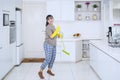 Pretty housekeeper dancing with a broom in kitchen Royalty Free Stock Photo