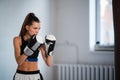 A pretty kickboxer girl is preparing for competitions in the boxing hall, practicing the technique of punches on a Royalty Free Stock Photo