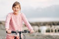 Pretty kid girl riding bicycle next to lake