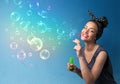 Pretty lady blowing colorful bubbles on blue background Royalty Free Stock Photo
