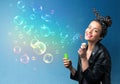 Pretty lady blowing colorful bubbles on blue background Royalty Free Stock Photo