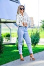 Pretty lady in blue jeans and white leather jacket enjoying sun.