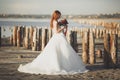 Pretty lady, bride posing in a wedding dress near sea on sunset