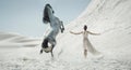 Pretty lady with huge horse on the desert