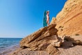 Pretty lady on rock with surfboard. Coastline and ocean view. Surfing sport, adventure time, beach day idea, copy space Royalty Free Stock Photo