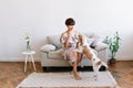 Pretty lady with shiny hair playing with beagle dog spending time at home after work. Indoor portrait of cute puppy Royalty Free Stock Photo