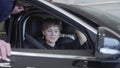 Pretty lady with short hair examines new car talking with unrecognizable salesman. Professioal salesman in suit