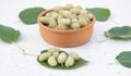 Pretty layout with stylish brown bowl with ripe berries lying on marble table with leaves.