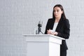 pretty lecturer, suffering from glossophobia, standing on podium tribune and holding container with pills.