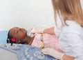 Afro girl lying on bed while getting ultrasound of thyroid. Royalty Free Stock Photo