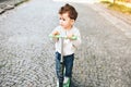 Pretty little boy riding scooter outdoor on the street Royalty Free Stock Photo