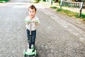 Pretty little boy riding scooter outdoor on the street Royalty Free Stock Photo