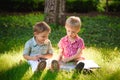 A pretty little boys reading a book on a green grass. Royalty Free Stock Photo