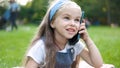 Pretty little child girl having conversation on her mobile phone in summer park Royalty Free Stock Photo