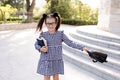 Pretty little child girl 5-6 year old playing outdoors wear glasses, stylish dress holding backpack. Back to school. Sweet smiling