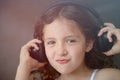 Pretty little curly girl in headphones listen music sound with pleasure grimace on her beautiful young face Royalty Free Stock Photo