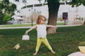 Pretty little cute child baby girl with basket play and have fun, rest on green grass lawn in park. Mother, little kid Royalty Free Stock Photo