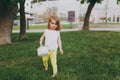 Pretty little cute child baby girl with basket walking, play and have fun on green grass lawn in park. Little kid Royalty Free Stock Photo