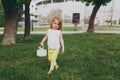 Pretty little cute child baby girl with basket walking, play and have fun on green grass lawn in park. Little kid Royalty Free Stock Photo