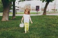 Pretty little cute child baby girl with basket walking, play and have fun on green grass lawn in park. Little kid Royalty Free Stock Photo