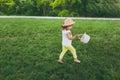 Pretty little cute child baby girl in hat with basket running, play and have fun on green grass lawn in park. Mother Royalty Free Stock Photo