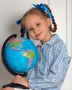 Pretty little European girl kid 6-7 years old holds a world globe in her hand. Distance online learning at home in Royalty Free Stock Photo