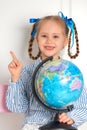 Pretty little European girl kid 6-7 years old holds a world globe in her hand. Distance online learning at home in Royalty Free Stock Photo