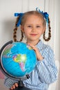 Pretty little European girl kid 6-7 years old holds a world globe in her hand. Distance online learning at home in Royalty Free Stock Photo