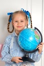 Pretty little European girl kid 6-7 years old holds a world globe in her hand. Distance online learning at home in Royalty Free Stock Photo
