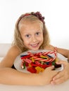 Pretty little female child eating dish full of candy caramel and sweet food