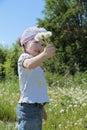 Pretty little gilr in hat holds dandelions and smiles