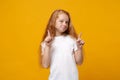 Pretty little ginger kid girl 12-13 years old in white t-shirt isolated on yellow wall background children studio Royalty Free Stock Photo