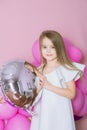 Pretty little girl with beautiful blonde hair in white dress alluring with pink balloons over pink background Royalty Free Stock Photo