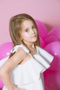 Pretty little girl with beautiful blonde hair in white dress alluring with pink balloons over pink background Royalty Free Stock Photo